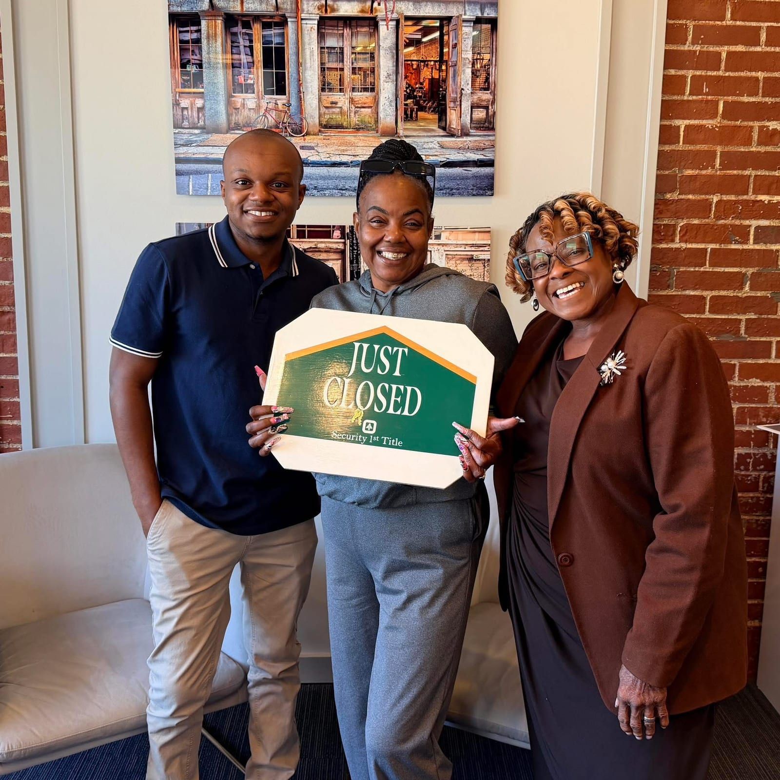Krishon with clients holding a Just Closed sign